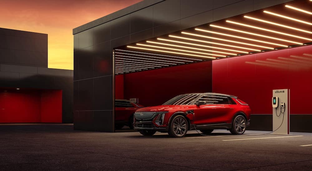 A red 2024 Cadillac LYRIQ is shown parked in a garage near a Cadillac dealer.