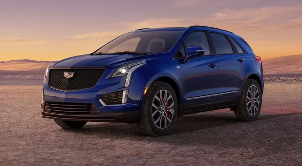 A blue 2024 Cadillac XT5 for sale parked in a field at sunset.