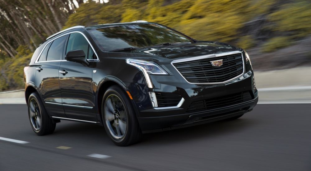 A black 2021 Cadillac XT5 Sport driving past blurred trees.