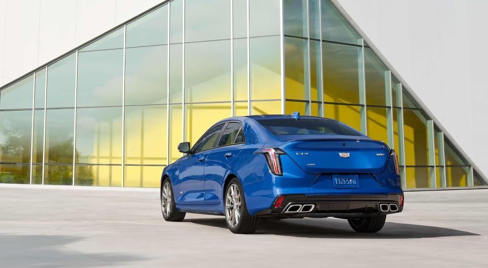 Rear view of a blue 2022 Cadillac CT4-V Blackwing parked outside a glass building.