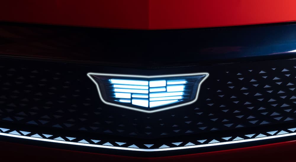 Close-up on the badge and grille of a red 2026 Cadillac OPTIQ-V.