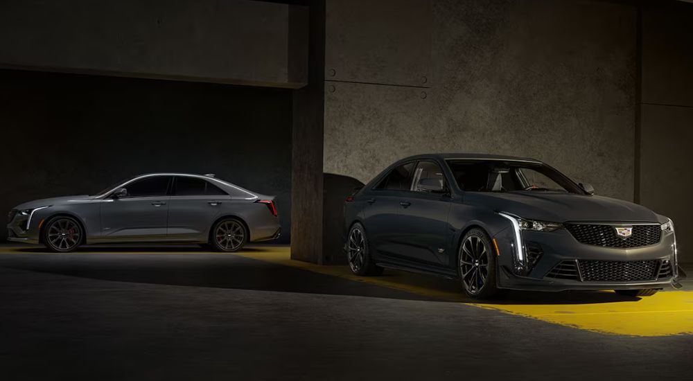 A silver 2026 Cadillac CT4-V and a grey CT4-V Blackwing parked in a parking garage.