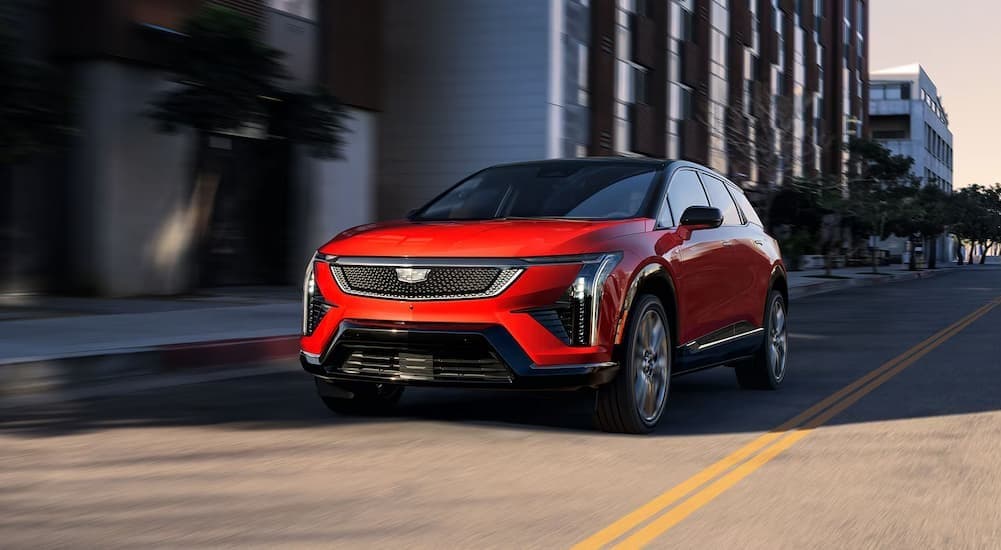 A red 2026 Cadillac OPTIQ driving in a city.