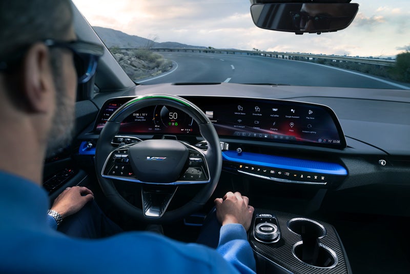 Front View of the 2026 OPTIQ-V Driving Through the Dusk Utilizing its Headlights | LaFontaine Cadillac Highland in Highland Charter Township MI
