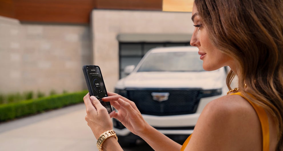 lady checking her mobile with a Cadillac vehicle background | LaFontaine Cadillac Highland in Highland Charter Township MI