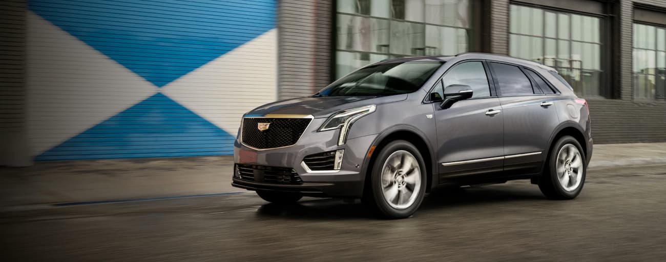 Grey 2021 Cadillac XT5 driving near a building.