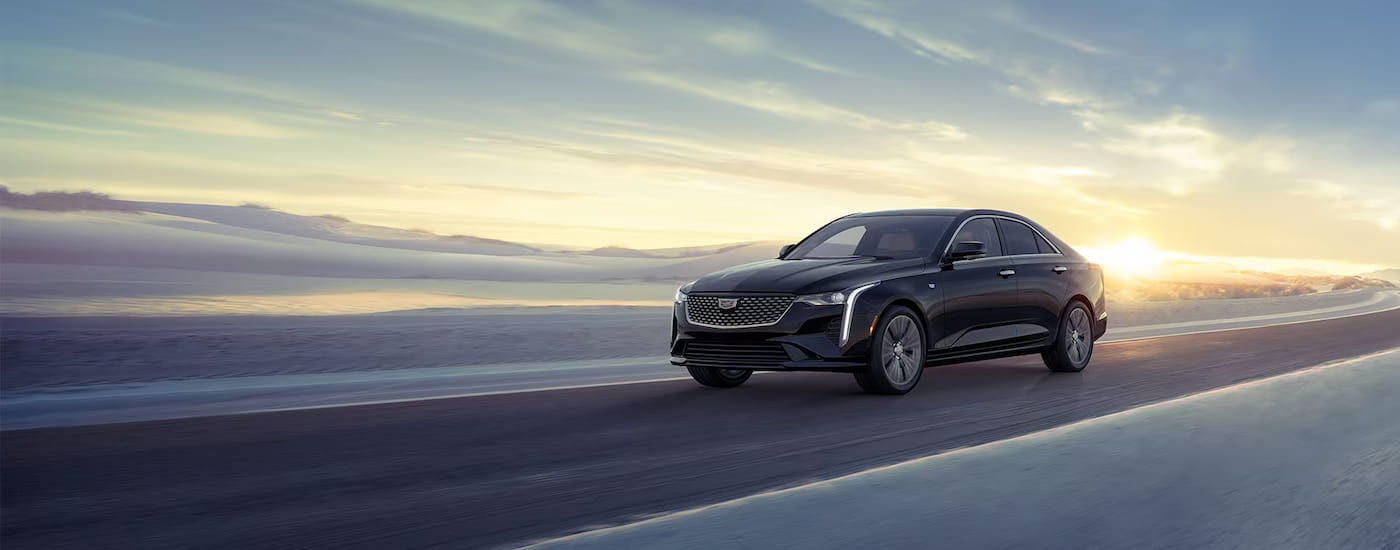 Black 2025 Cadillac CT4 driving down a road.