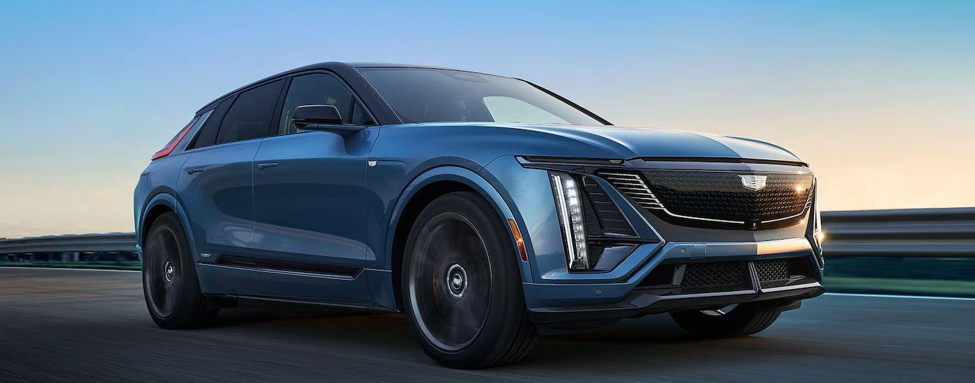 Blue 2026 Cadillac LYRIQ driving down an open road.
