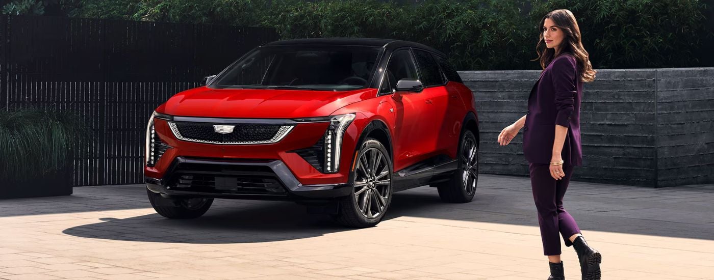 Red 2026 Cadillac OPTIQ parked with a woman walking toward it.