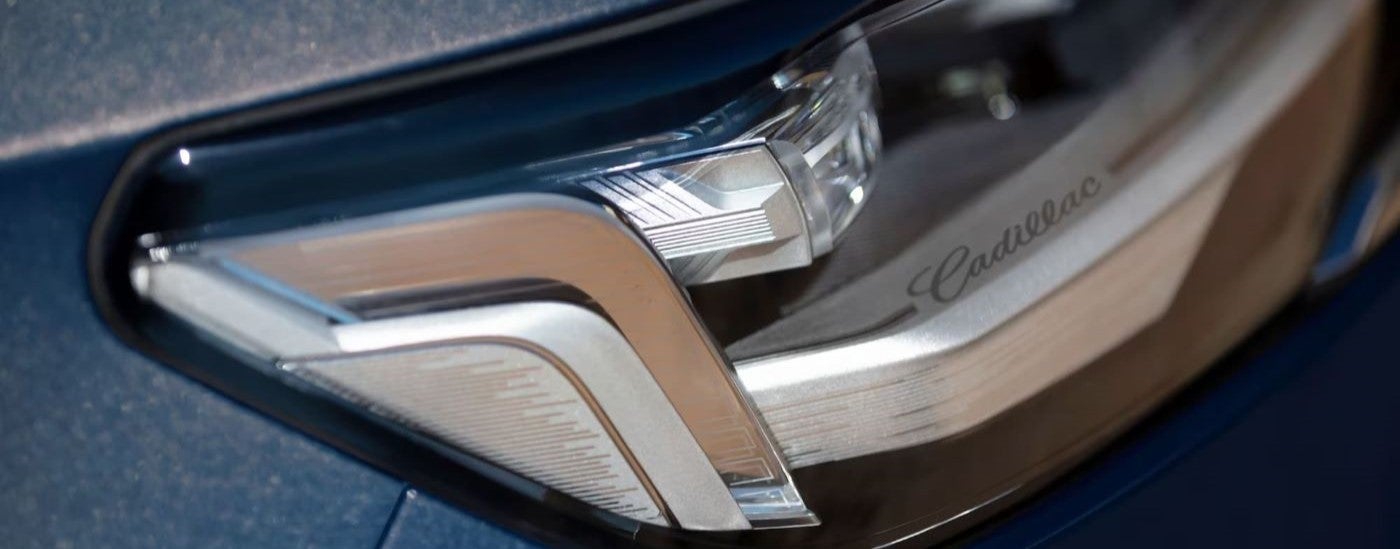 A close up shows the headlight on a blue 2023 Cadillac Escalade.