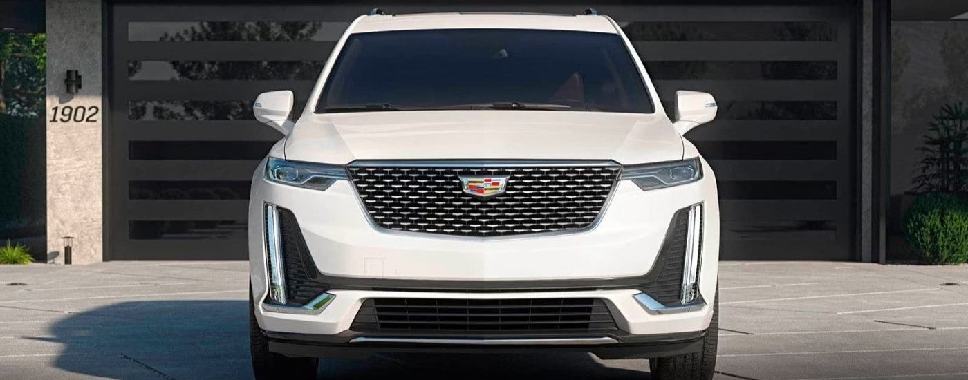A white 2023 Cadillac XT6 is shown in front of a garage after leaving a Cadillac dealer.