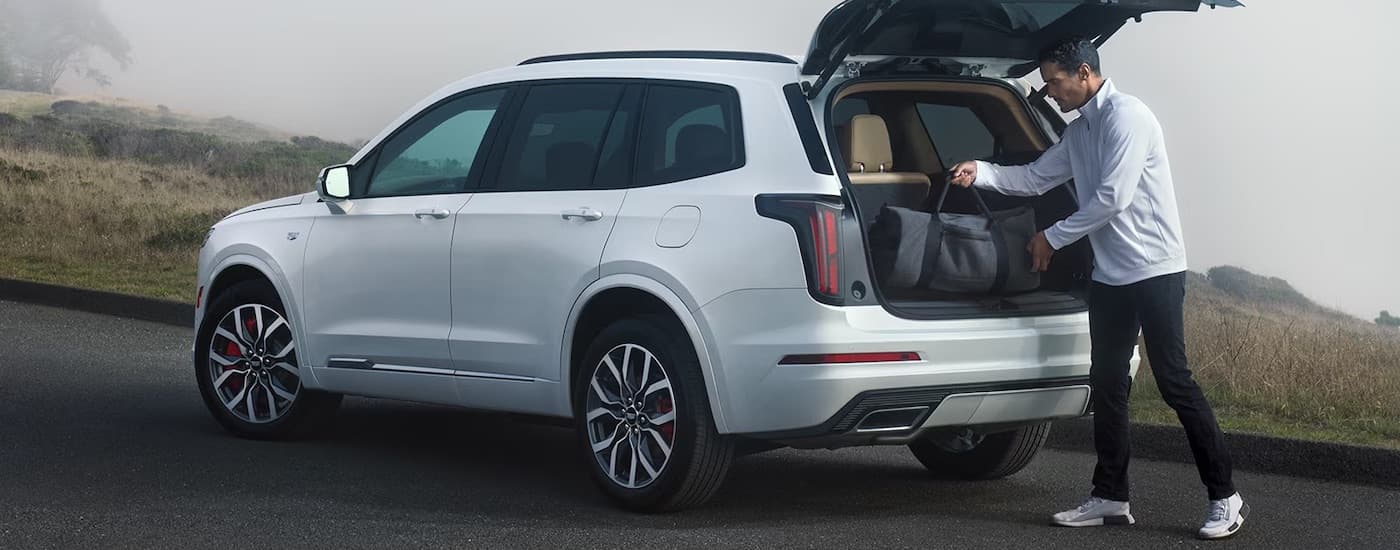 A man opening the hatchback of a white 2024 Cadillac XT6.