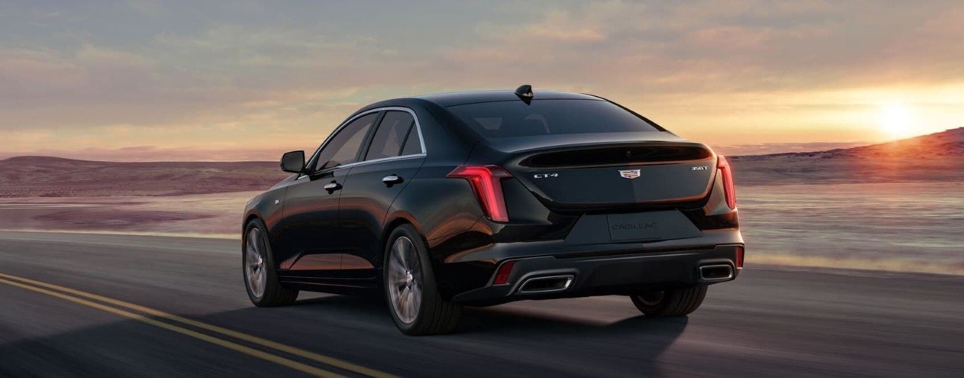 A black 2023 Cadillac CT4 is shown from the rear driving on an open road.