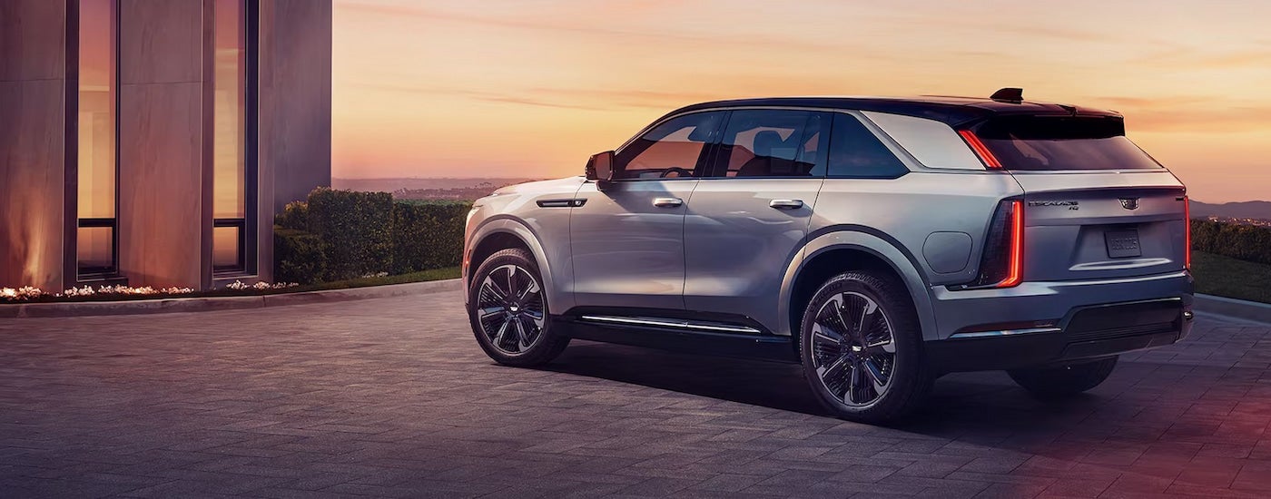 Rear view of a silver 2025 Cadillac Escalade IQ parked near a modern building.