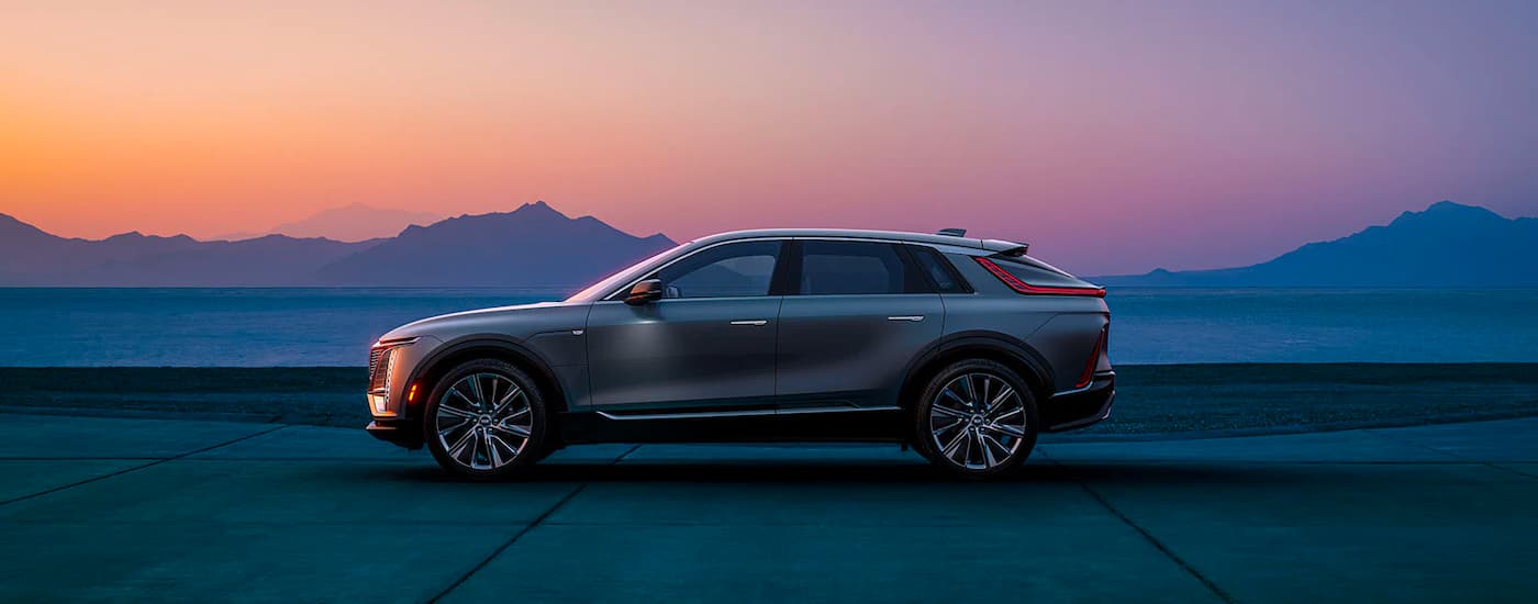 A silver 2023 Cadillac LYRIQ is shown parked near mountains.