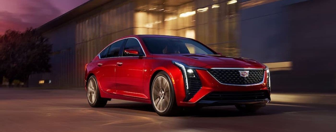 A red 2026 Cadillac CT5 driving to a car dealership near Dearborn.