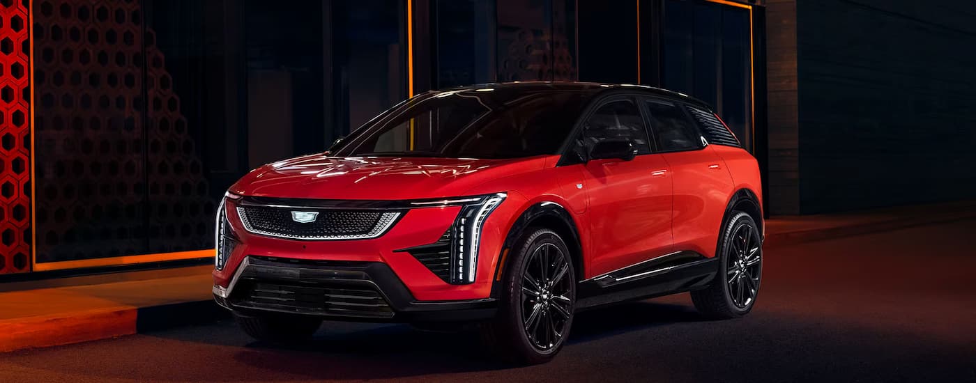 A red 2025 Cadillac OPTIQ parked in a city at night